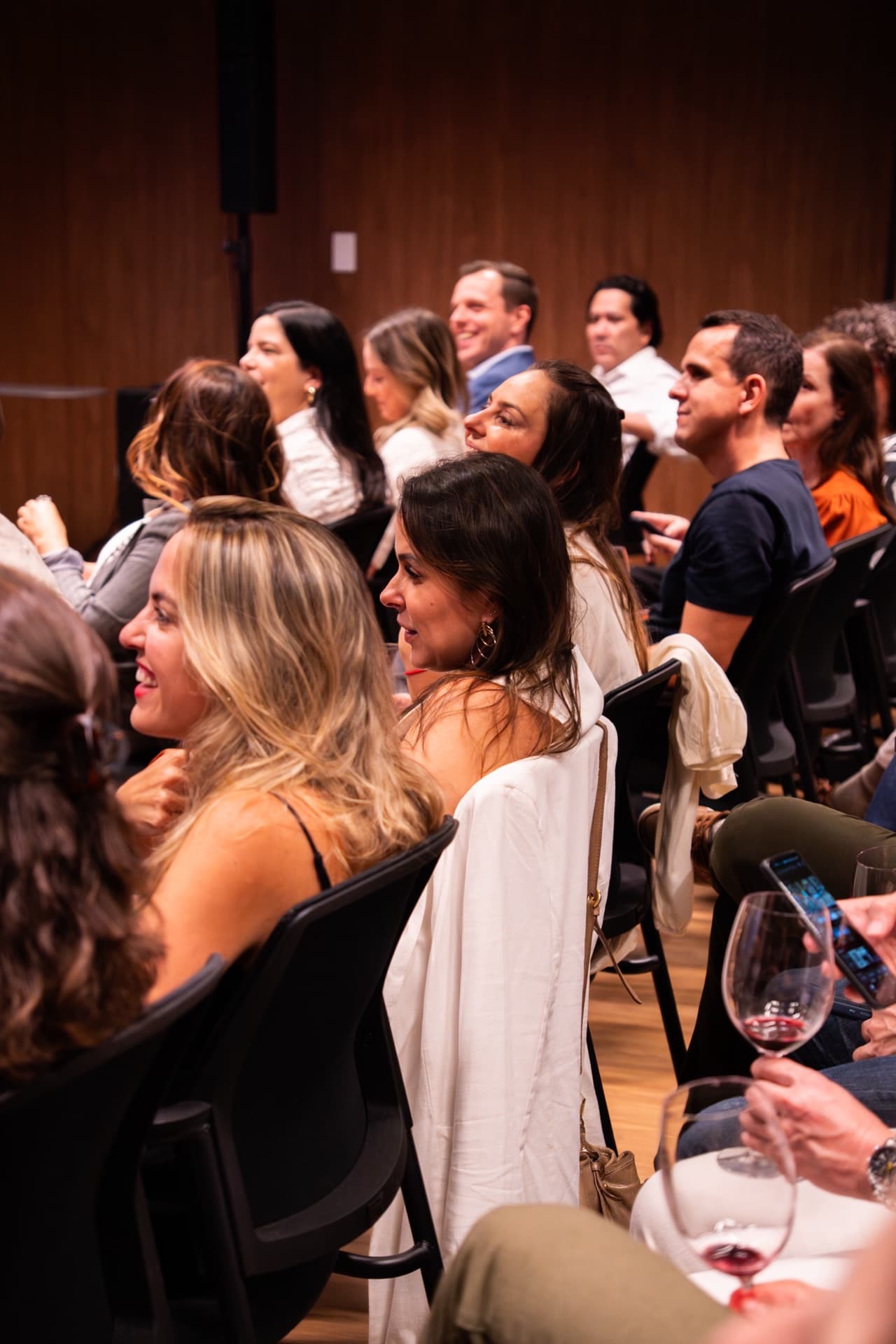 Participantes assistindo palestra com taças de vinho